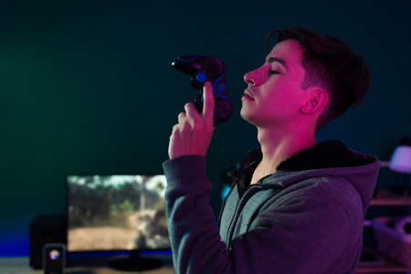 Ready for a game competition. Profile of a handsome gamer holding a gamepad and ready to play a videogameの写真素材