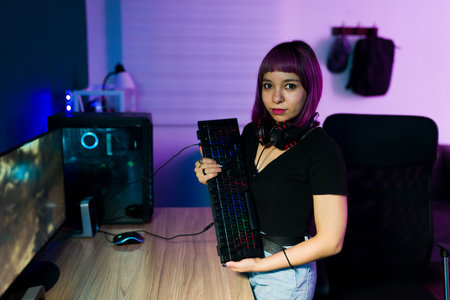 I love playing on my pc. Hispanic young woman with a headset hugging her computer keyboardの写真素材