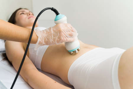 Cosmetology concept. Close up of a caucasian woman receiving an anti aging treatment for her stomach...