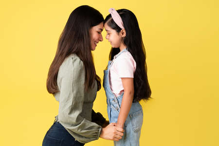 Mom and daughter love. Happy young woman and little girl face to face touching foreheads while smilingの写真素材