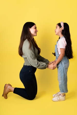 Hispanic mother kneeling and talking to her elementary daughter about love, affection and positive emotionsの写真素材