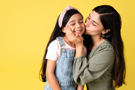 Devoted mother giving a kiss to her adorable little daughter while sharing lovely family moments