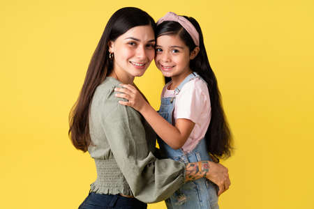 Family bonding. Cheerful hispanic mother and daughter hugging. Lovely mom and little girl with long hairの写真素材