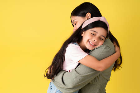 I love you so much. Cute hispanic girl giving a hug to her beautiful mother and smilingの写真素材