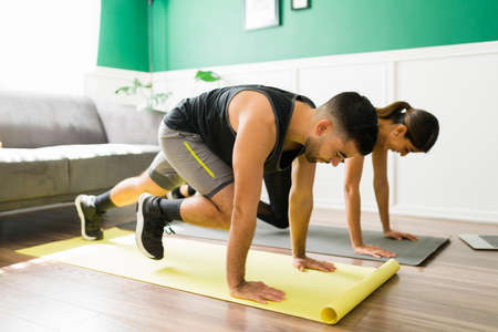 Cardio workout. Active couple training at home and doing mountain climbers exercises