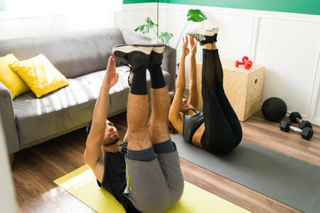 Warm up. Attractive man and young woman stretching their body before starting a cardio workout at...
