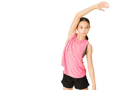 Beautiful caucasian girl working out and stretching her arms against a studio backgroundの写真素材