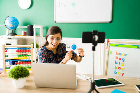 Vocabulary lessons. Happy female teacher using flashcards to teach the letters and the alphabet to preschool little kids during a virtual classの写真素材