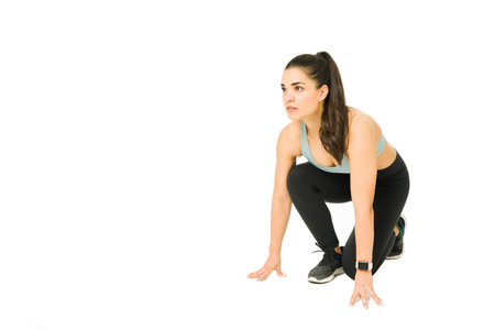 Athletic fit woman preparing to start her training on a running track against a white background