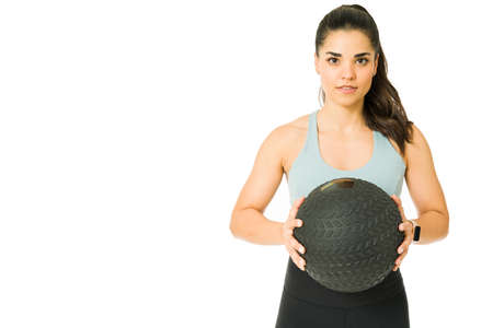 Fitness young woman looking at the camera while using a slam ball for her high intensity interval trainingの写真素材