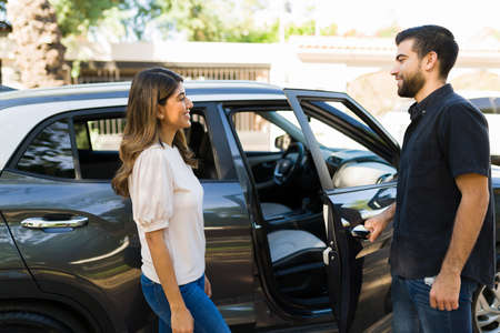 Happy boyfriend opening the car door for his girlfriend. Attractive couple in their 20s going out on...