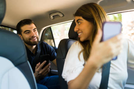 Happy female driver and passenger looking at the GPS on the mobile app on the smartphone while driving to a destinationの写真素材