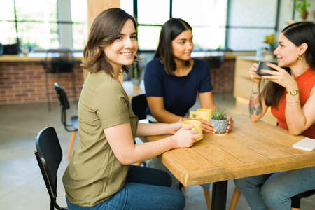 Enjoying hanging out with friends. Beautiful young women smiling while talking with her best friends at a restaurantの写真素材
