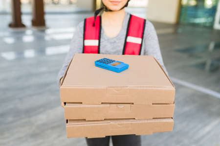 Close up of a young woman and delivery person delivering pizza for a mobile service app. Customer...