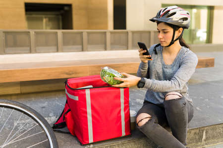 Working delivery woman taking a picture of the customer's food before delivering the orderの写真素材
