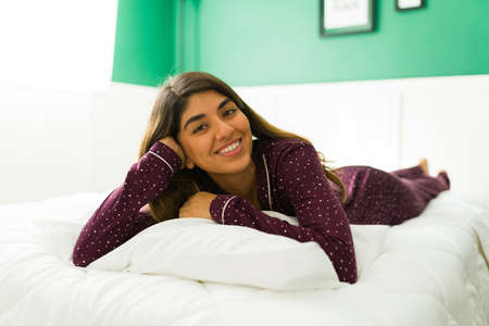 Attractive young woman lying on a comfortable bed and relaxing during a leisure time at homeの写真素材