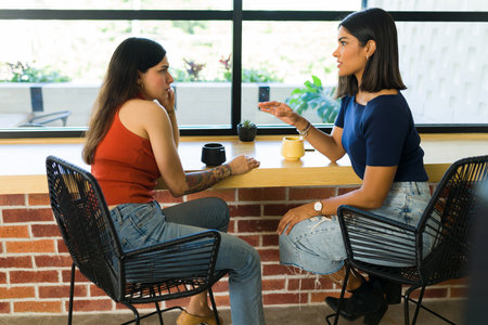 Female best friends catching up and having a deep conversation. Young women talking on a coffee shopの写真素材
