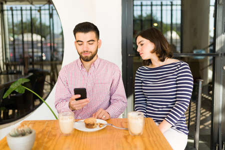 I'm afraid of cheating. Suspicious woman feeling insecure and worried while spying her boyfriend texting on the smartphoneの写真素材