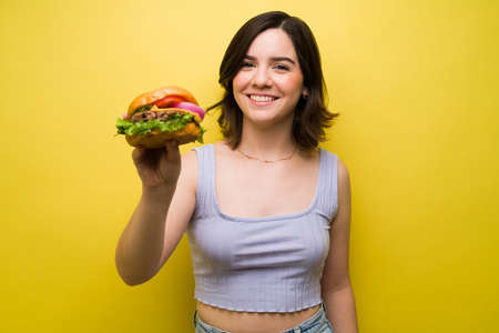 I'm having a delicious lunch. Portrait of an attractive caucasian woman holding a hamburgerの写真素材