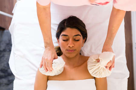 Top view of an attractive young woman relaxing with compress balls and a herbal treatmentの写真素材