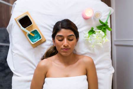 High angle of an attractive hispanic woman going to the spa and relaxing with a facial treatmentの写真素材