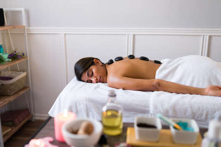 Relaxed young woman getting a spa treatment with hot stones at the wellness centerの写真素材