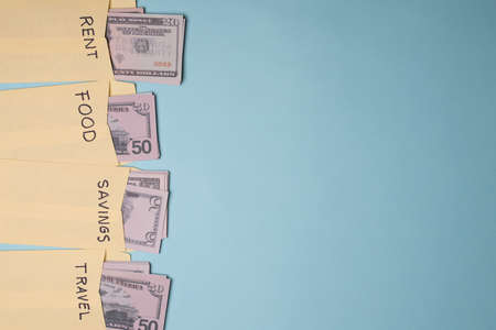 Yellow envelopes full with money destined to pay rent, food, travel and savings next to copy space