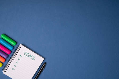 Notebook and colorful markers on a blue background with copy space. New year goals and work...