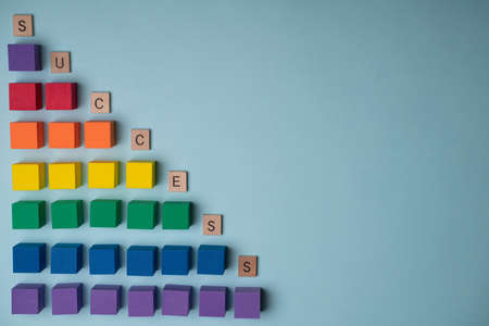 Paving the way for success. Colorful wooden cubes toys guiding the path to success in front of a blue backgroundの写真素材