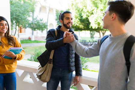 How are you? Attractive young man smiling and greeting a friend at college before a class