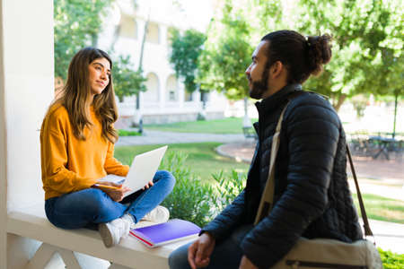 College friends talking and doing research online on the laptop for their homework before a lectureの写真素材