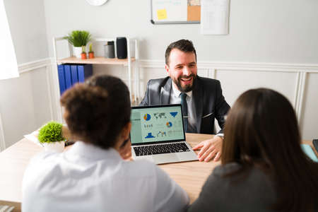 Cheerful accountant showing their investments, budgets and credit loans to their clients on the laptopの写真素材
