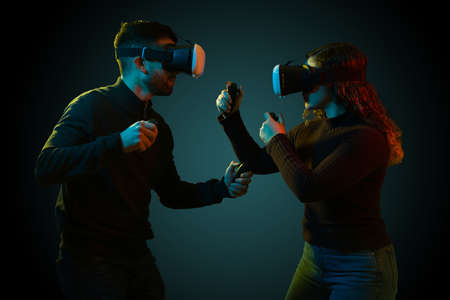 Competitive video game tournament. Gamer young man and woman on a video game match using virtual reality glasses and joysticksの写真素材