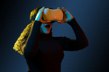 This is amazing! Cheerful woman with a VR headset looking surprised with her mouth open while watching a virtual reality videoの写真素材