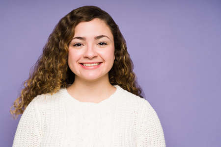 Gorgeous caucasian woman looking at the camera and smiling while feeling cheerful against a purple...