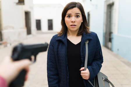 Point of view of a beautiful woman looking scared while being robbed and threatened with a gun by a...