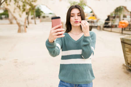 Beautiful caucasian woman using a lipstick and beauty products while filming a video for her thousands of social media followersの写真素材