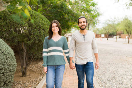 Beautiful girlfriend and handsome boyfriend holding hands. Couple in love dating and walking at the park on a relaxing dayの写真素材