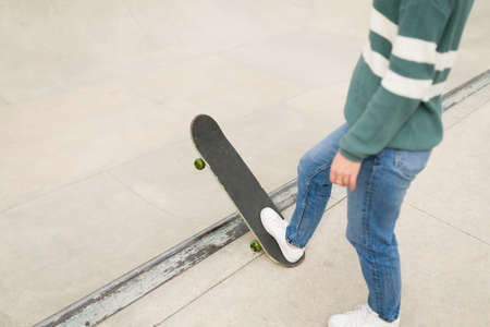 Close up of a young woman in casual clothes using a skateboard at the skatepark and learning some...