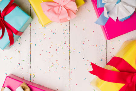 Beautiful wrapped birthday presents on a wooden white table with colorful sprinkles candies