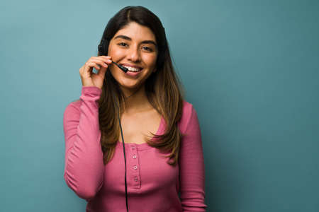 Customer service  representative. Happy latin woman wearing a headset and working at the call center