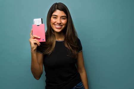 Ready for vacations. Latin young woman about to travel showing her plane tickets and passport