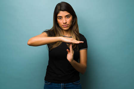 Angry young woman making the time-out gesture and showing the time is up sign