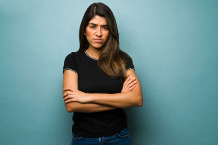I can't stand it. Upset hispanic woman looking very angry with her arms crossed while looking at the...