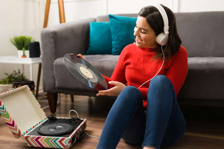 Music has saved me. Artistic woman sitting in the living room floor while enjoying music on vinyl...