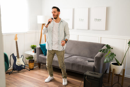 Talented male singer. Inspired handsome man singing and rehearsing a song with a microphoneの写真素材