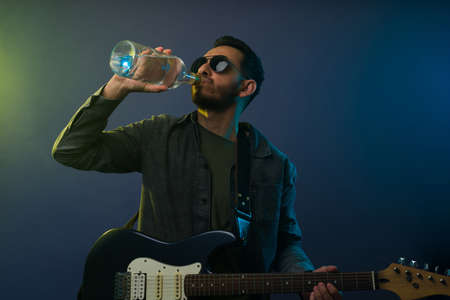 Hispanic young man drinking alcohol while performing during a rock and roll concertの写真素材