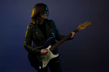 Talented female artist playing the electric guitar and singing. Rock and roll singer rehearsing for a concertの写真素材