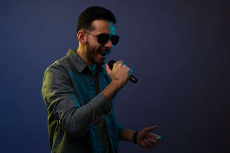 Attractive hispanic rock singer singing with a microphone and rehearsing for his music concertの写真素材