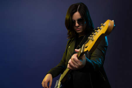 Rock and roll female guitarist wearing a leather jacket playing the electric guitar and rehearsing for a concertの写真素材